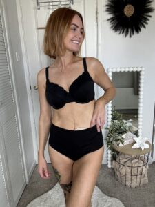 Our ambassador Maryrose poses gracefully in black underwear, embodying confidence and allure as her stoma bag peaks through.
