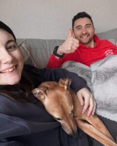 Amy and her husband posing for a photo alongside their dog!
