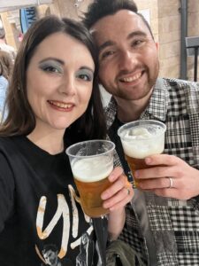 Amy and her husband posing for a selfie, with a beer in hand.