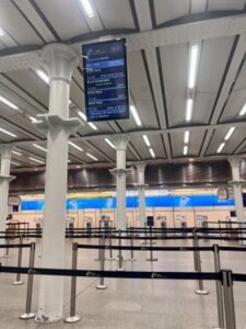 A spacious airport terminal featuring a large digital screen displaying flight information.