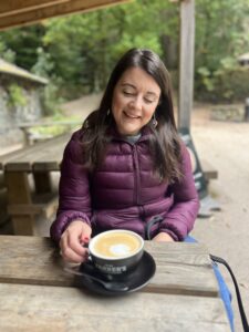 Amy smiling, with a coffee, showing how you can do normal everyday things with a stoma.