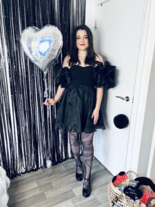 Amy, all dressed up ready to go out, smiles while holding a foil balloon - showing that you can live life with a stoma!